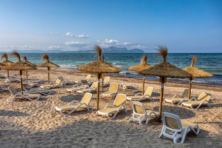 Can Picafort Beach with straw umbrellas and sun loungers, morning with no people, against the turquoise sea. Can Picafort, Balearic Islands Mallorca Spain. Travel agency vacation concept.の写真素材