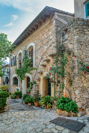 Narrow street in the Valldemossa with lots of ubiquitous flowers. Architectural treasures - Magic of Valldemossa's historic center and its Mediterranean architecture. Balearic Islands Mallorca Spain.のeditorial素材