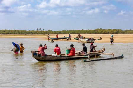 MORONDAVA, MADAGASCAR - NOVEMBER 22, 2022: Malagasy family in traditional wooden boat crossing River in Morondava, Madagascar.のeditorial素材