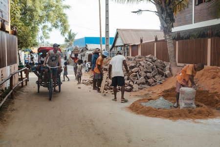 Morondava, Madagascar - November 3rd, 2022: Malagasy men working hard, manually carrying construction stones.のeditorial素材