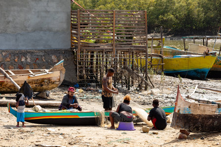 Morondava, Madagascar - November 3, 2022: Fisherman and woman repairing fishing nets at the estuaries of a river, canal Hellot. The woman has a traditionally Malagasy painted faceのeditorial素材