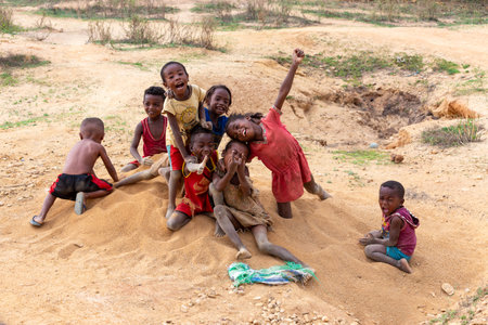 Ilakaka, Madagascar - November 24, 2022: Curious group of children looking at a tourist near the gem mining fields in Ilakaka. The children are descendants of local miners and live in a simple village.のeditorial素材