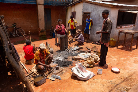 Mandoto, Madagascar - November 9th 2022 - A Malagasy couple runs a blacksmithing business in Mandoto. A Malagasy blacksmith works on iron while his wife operates the bellows in their workshop.のeditorial素材