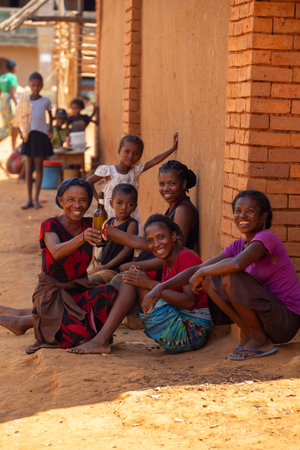 Vohitsaoka, Madagascar - November 17, 2022: Local woman drinking beer on the street at noon.のeditorial素材