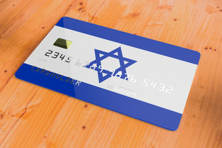 Plastic credit or bank debit card with country flag of Israel national banking system isolated on wooden table close up concept 3d rendering imageの写真素材