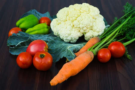 tomatoes, carrots, peppers and cauliflower on a dark wooden backgroundの写真素材