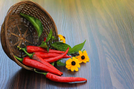 hot pepper with flowers in a basket on the tableの写真素材