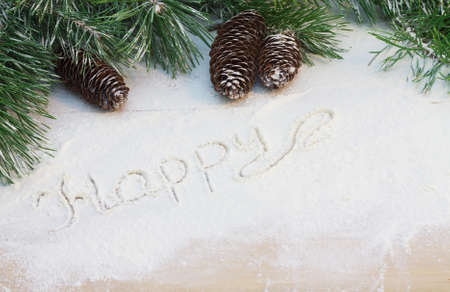 pine branches and cones in the snow with the words "Happy"の写真素材