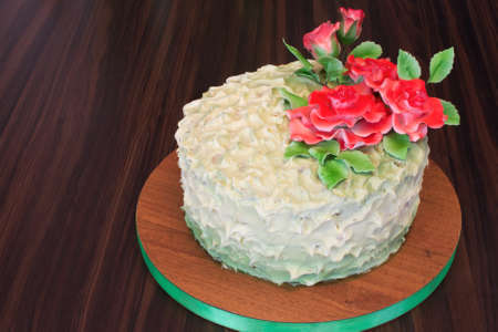 cream cake with red sugar roses on a dark wooden backgroundの写真素材