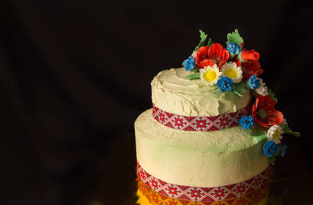 cake in the Ukrainian style with sugar poppies and daisies on blurry black backgroundの写真素材