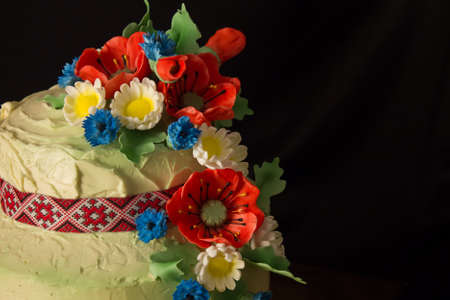 closeup cake in the Ukrainian style with sugar poppies and daisies on blurry black backgroundの写真素材