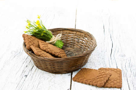 basket with cookies and a bunch of small yellow flowers on white wooden background blurred.の写真素材