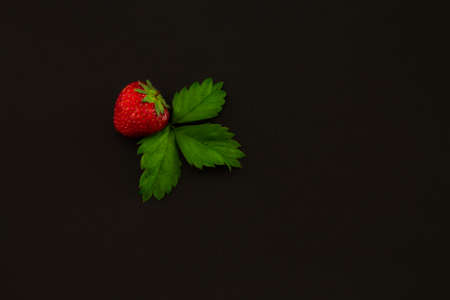 strawberry with leaves on a black textural backgroundの写真素材