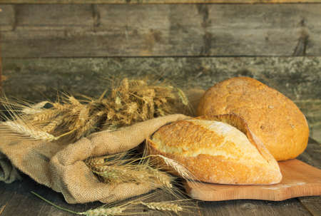 Bread with ears of wheat on a rough cloth on a wooden background