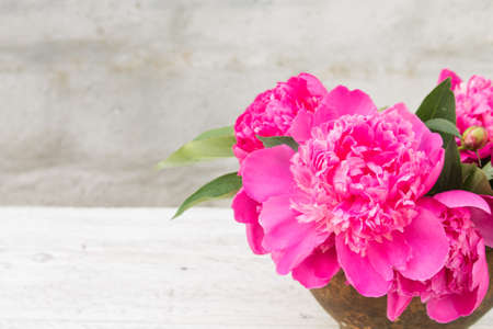 bouquet of pink peony in an old clay pot closeup on a light blurred backgroundの写真素材