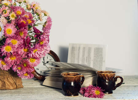 bouquet of pink carnations on a table with a book and cupの写真素材