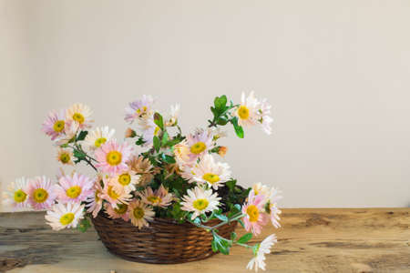 bouquet of pale pink chrysanthemums in a wicker basket on a wooden table on a light backgroundの写真素材
