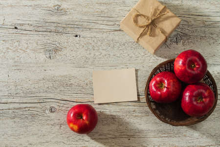 red apples with a gift and a blank sheet on a light wooden backgroundの写真素材