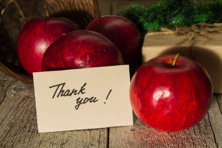 red apples with a gift and a postcard with text Thank You on a wooden backgroundの写真素材