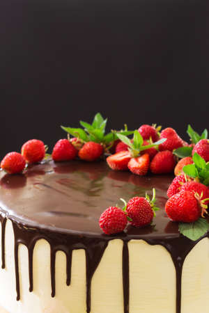 Background of a cake with melted chocolate with a strawberry close-up on a black background. Vertical photo. Selective focusの写真素材
