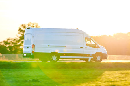 White Van driving fast on a country road. Delivery Van driving at sunset in autumn season.の写真素材