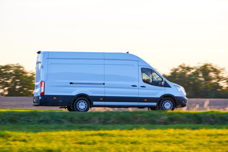 White Van driving fast on a country road. Delivery Van driving at sunset in autumn season.の写真素材