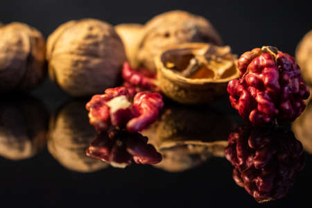 Pink walnut kernels on a dark reflective table. Black background