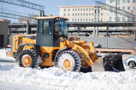 Wheel loader cleaning road from snow in Russia