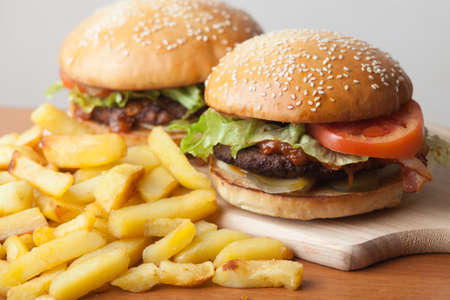 Fastfood burgers and fries lies on wood table