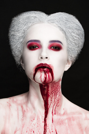 Mysterious beauty portrait of snow queen covered with blood. Bright luxury makeup. Gore dripping from the mouthの写真素材