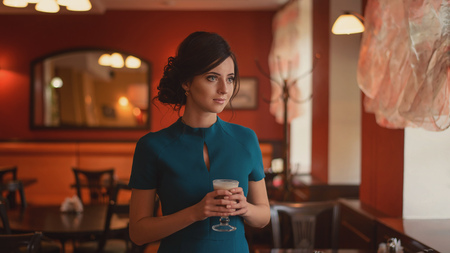 Pensive pretty girl in classic elegant dress standing at the cafe going to drink coffeeの写真素材