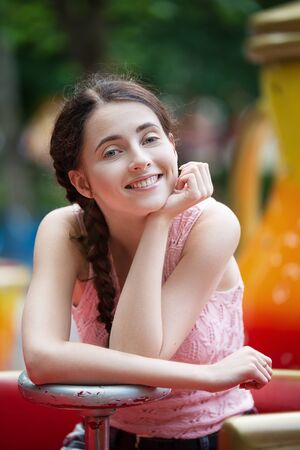 Attractive happy smiling girl in an amusement park sitting on carouselの写真素材