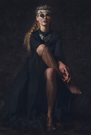 Queen of darkness in black fantasy costume on dark gothic background. High fashion beauty model with dark makeupの写真素材