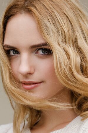 Dramatic portrait of a young beautiful blonde woman with long curly hair