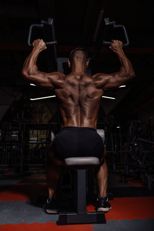 Handsome man with big muscles working out in gym. Muscular bodybuilder doing exercisesの写真素材