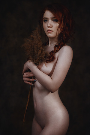 Fine art portrait of naked redhead woman posing over vintage background. Conceptual artistic photo of a sexy lady in a retro interiorの写真素材