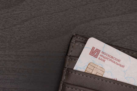 Debit card of Moscow Industrial Bank in a wallet on a wooden background