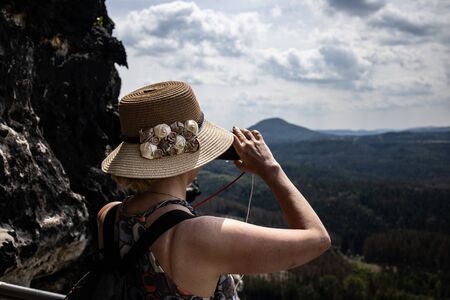 A tourist in a hat photographing the landscape. Czech Switzerland National Park. A national park famous for its sandstone formations, wild valleys and frozen waterfalls.の写真素材