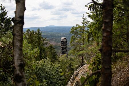 A upright rock in the midst of trees, pravcicka brana. Czech Switzerland National Park. A national park famous for its sandstone formations, wild valleys and frozen waterfalls.の写真素材