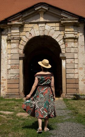 Elegant woman in a hat walking to a historic building, Czech Republicの写真素材