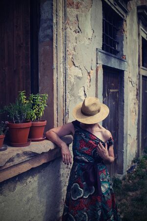 Elegant woman in a hat standing by the window of an old house, Czech Republicの写真素材