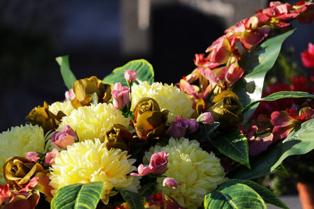 Bouquet of yellow and red flowers with green leaves in sunlight