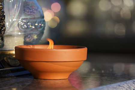 Candle light in a clay pot on the table with bokeh backgroundの写真素材