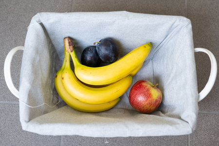 Bananas and apples in a basket on a kitchen countertop.の写真素材