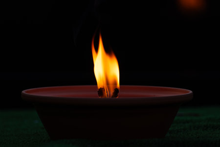 Close up of burning candle on green grass with black background, selective focus