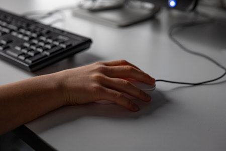 Close-up of a woman's hand using a mouse on a deskの写真素材