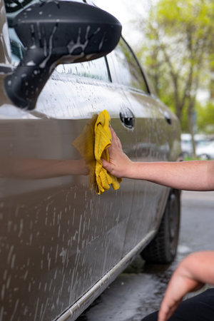 Man cleaning a car with a microfiber cloth and a ragの写真素材