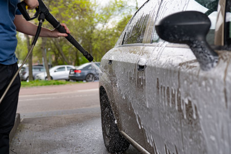 Man washing his car with high pressure water jet in a car washの写真素材