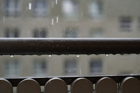 Rain drops on a metal fence. Rainy day in the city.の写真素材