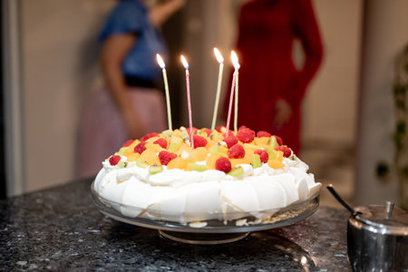 Birthday cake with candles on the background of a girl in a red dressの写真素材